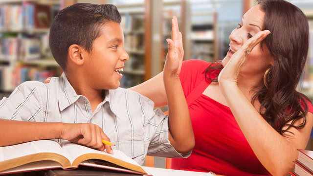 Latino student and teacher high five while studying at a local library.