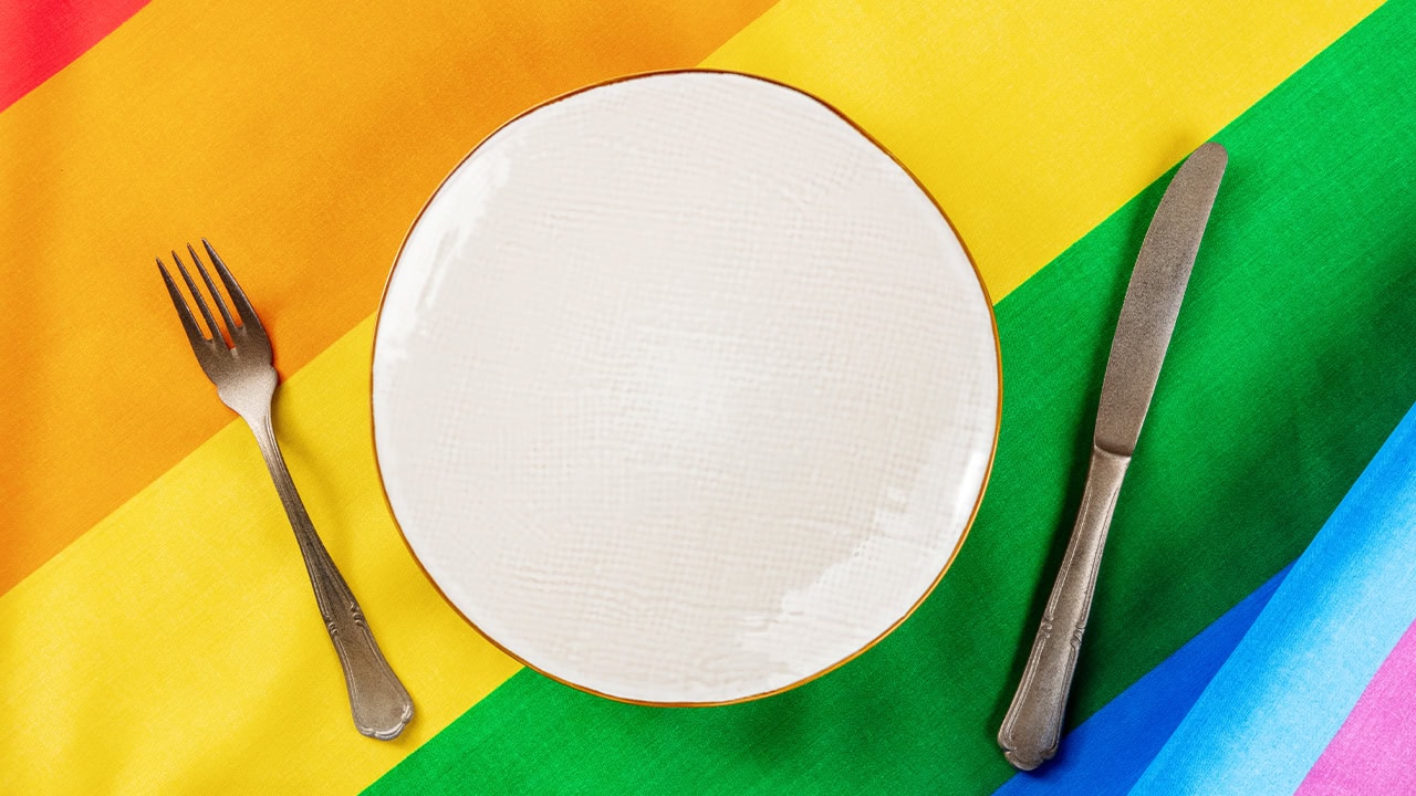 LGBT event dining table with rainbow flag tablecloth.