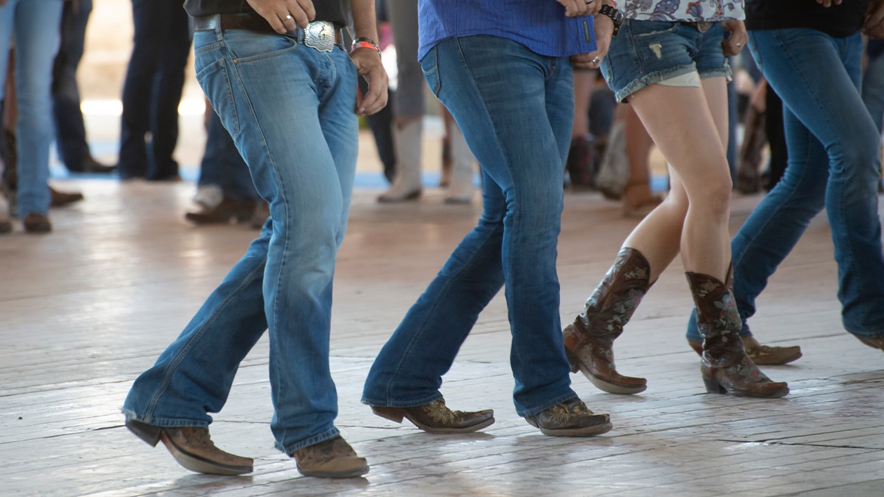 Men and woman country line dancing wearing cowboy boots.