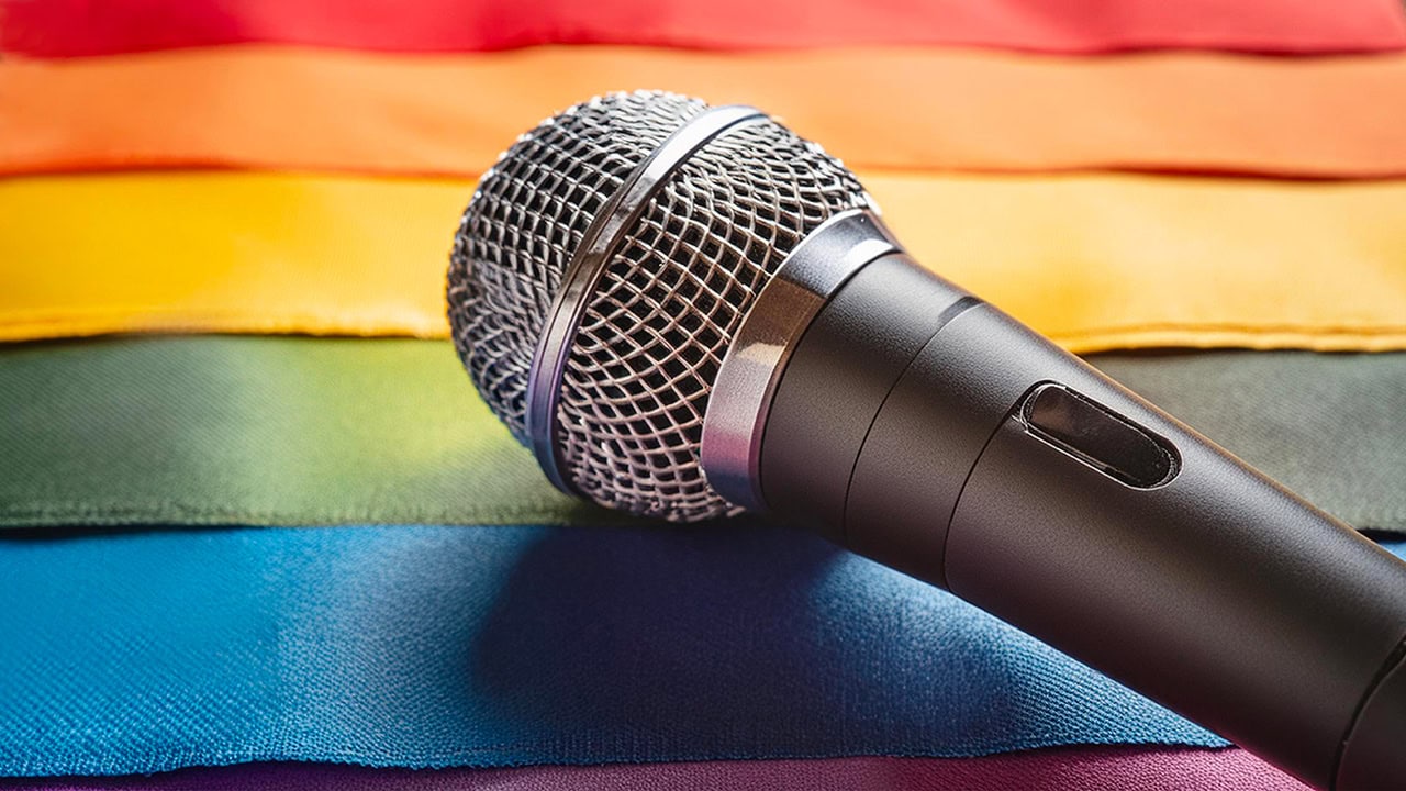 Microphone laying on LGBTQA+ rainbow Pride Month flag.