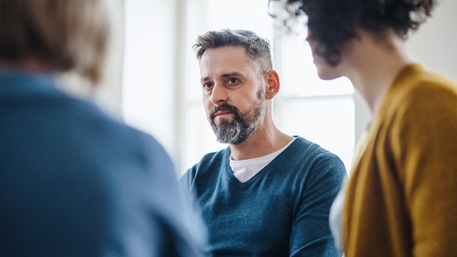 Middle-aged male and female residents attending a group therapy session.