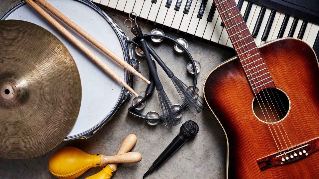 Musical instruments on floor including a guitar, snare drum, keyboard, and tambourine. Image produced by More Jersey.