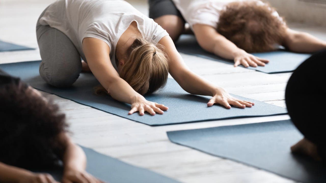 New Jersey group yoga class participants performing Balasana stretching pose on mats.