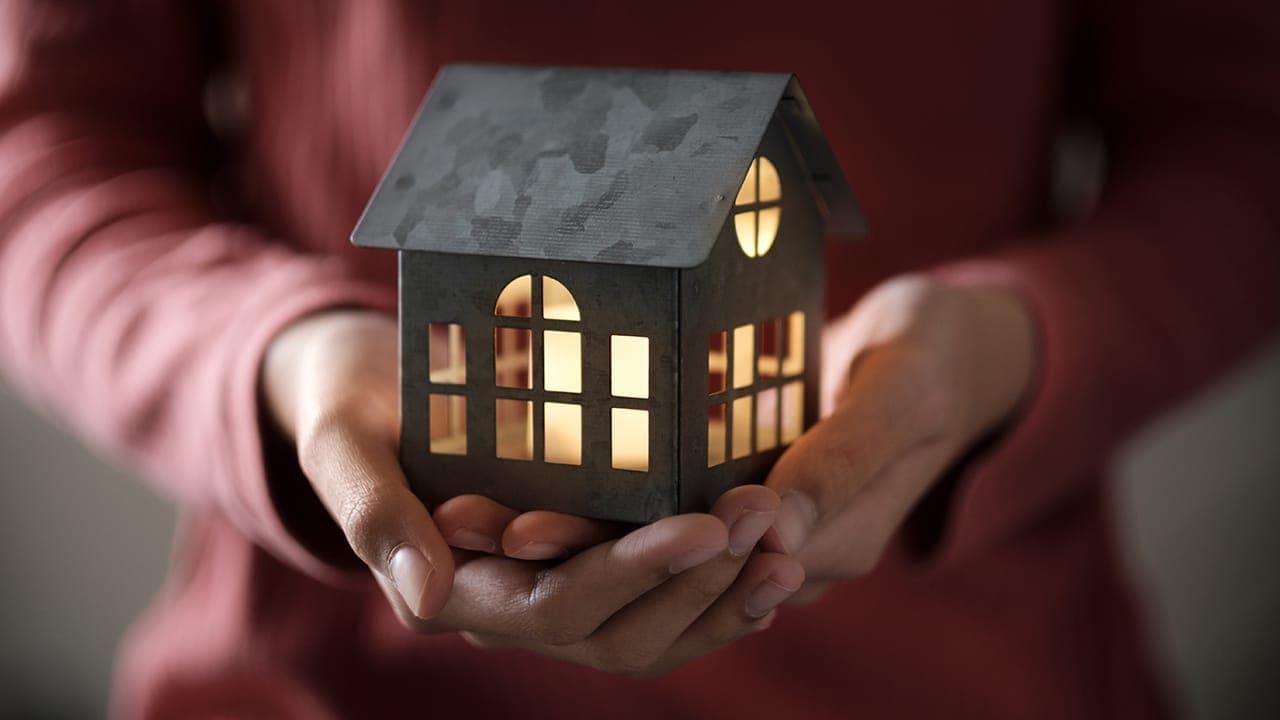 New Jersey resident holding a small model house. Image produced by More Jersey.