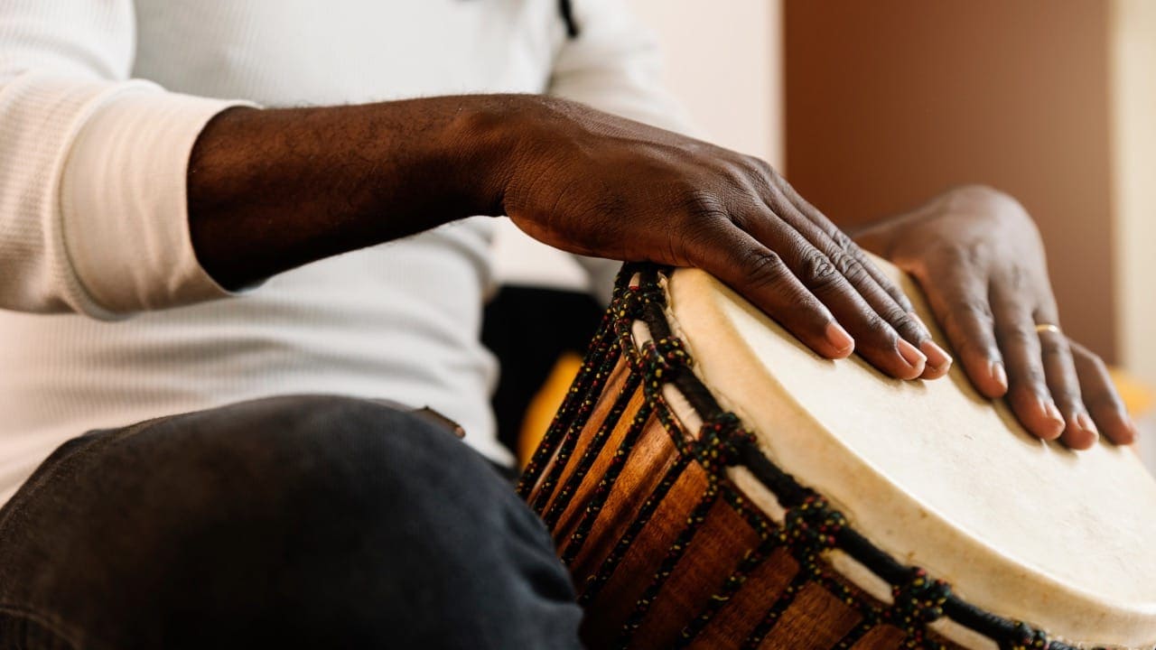 New Jersey resident playing African drum at cultural event.