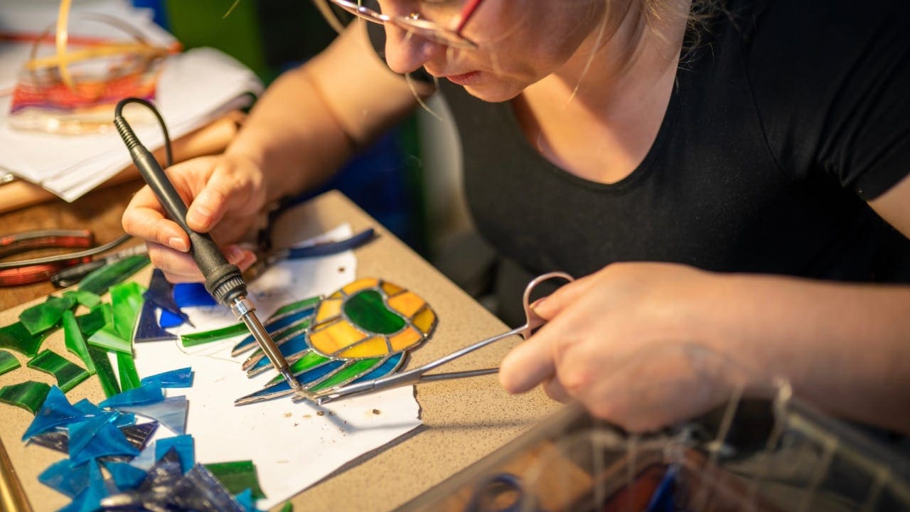 New Jersey resident soldering stained glass window during workshop.
