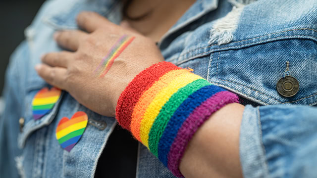 New Jersey resident wearing a rainbow flag wristband and a jean jacket with rainbow pins.