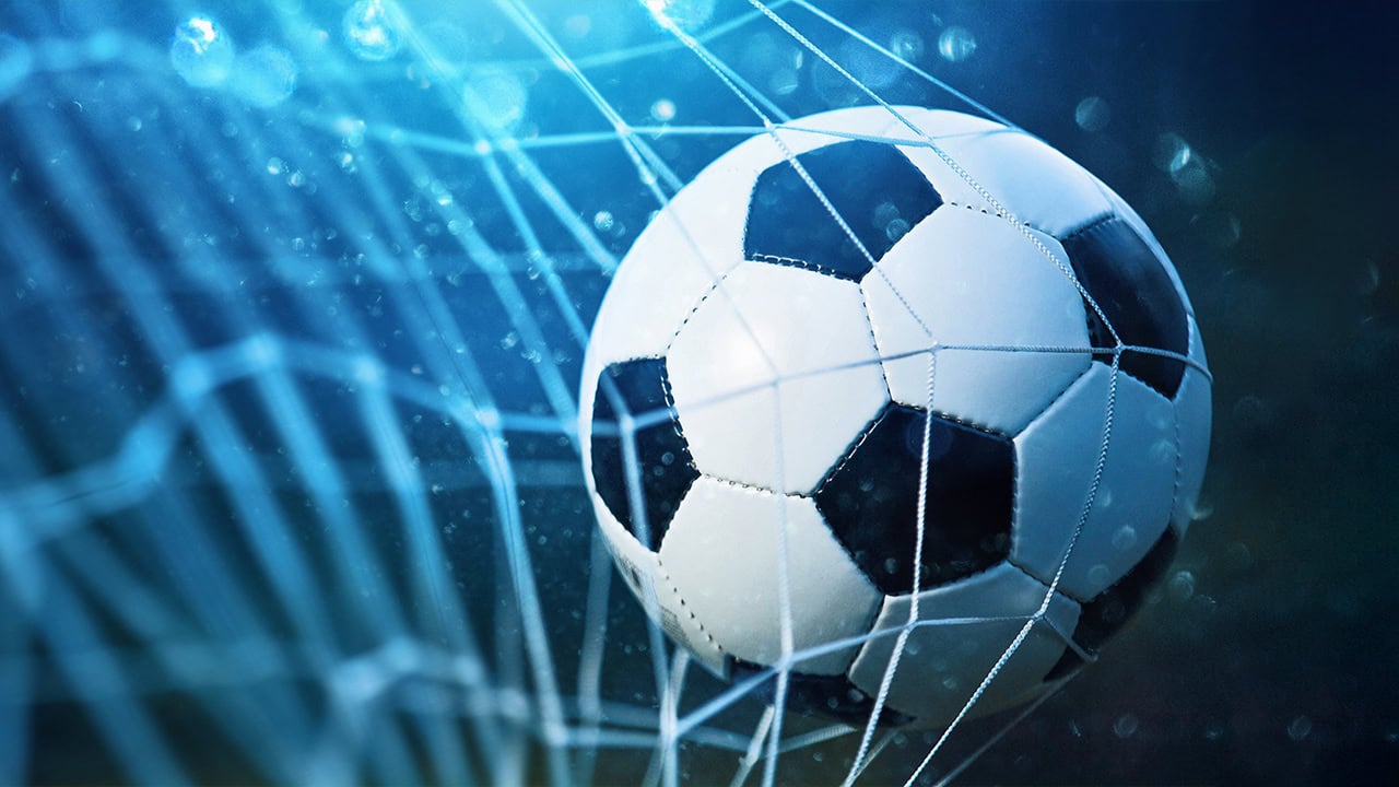 Soccer ball kicked into the net as a goal. Image produced by More Jersey.