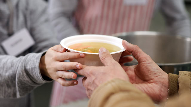 Volunteer serving hot soup at New Jersey community charity donation center.