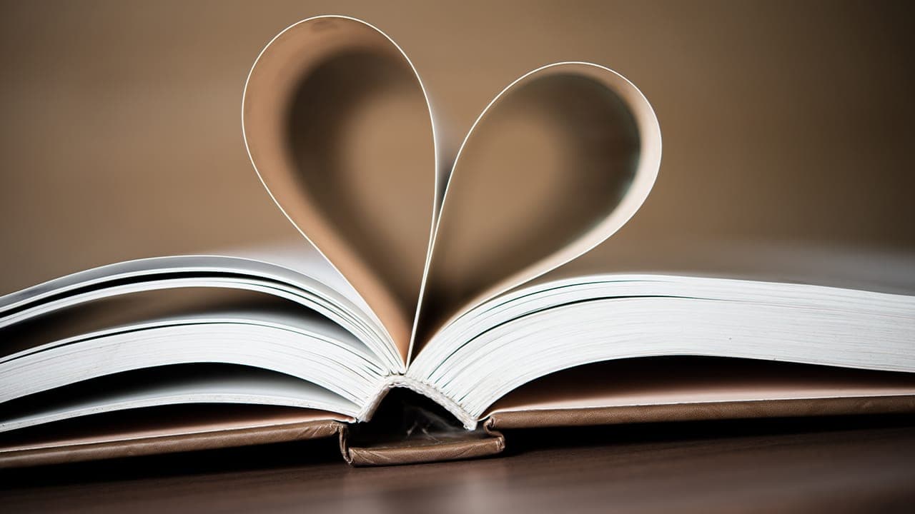 Pages of a book curling to form the shape of the heart.