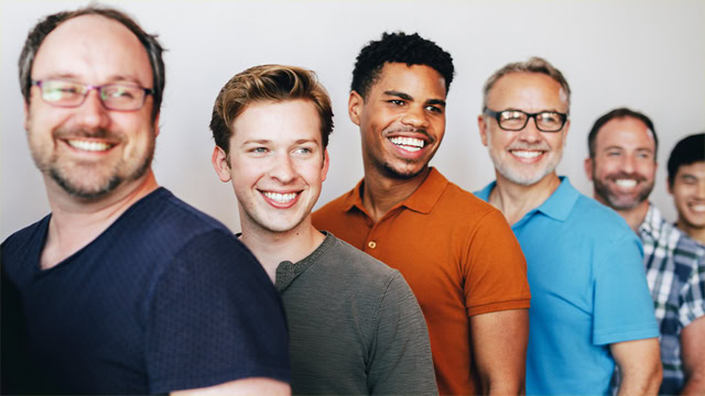 Professional gay men smiling for a group photo.