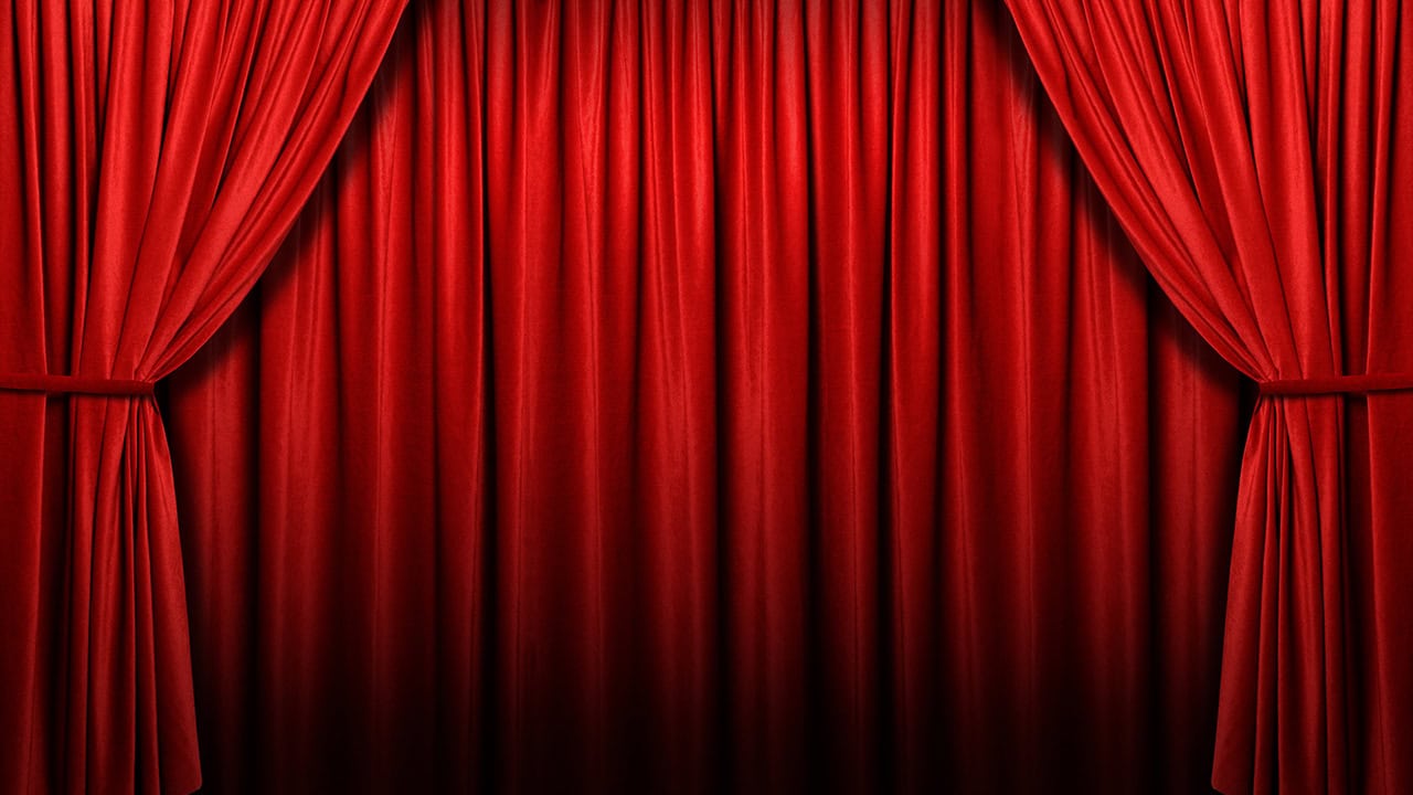 Red theatrical curtain closed on stage. Image produced by More Jersey.