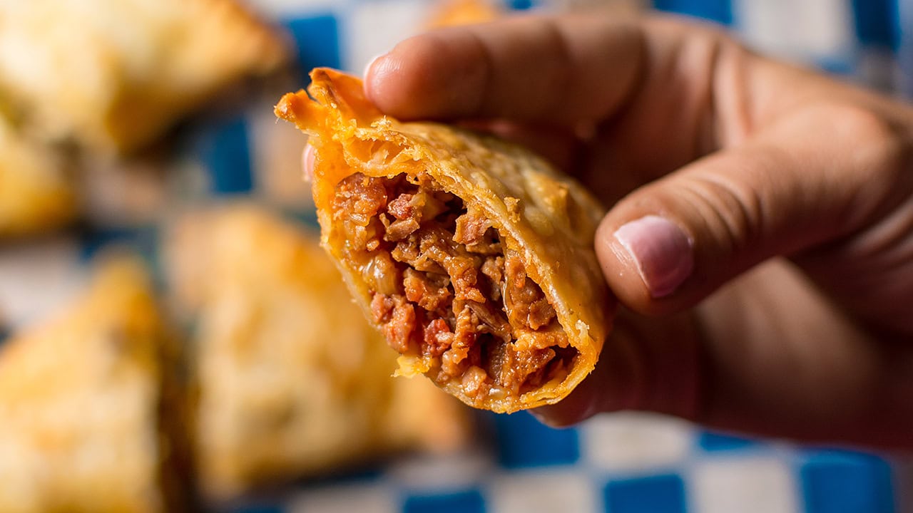 Resident holding deep fried empanada. Image produced by More Jersey.