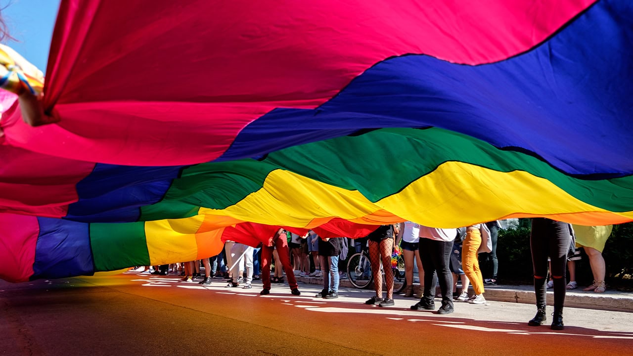 Residents together carrying giant rainbow flag at New Jersey Pride march event.