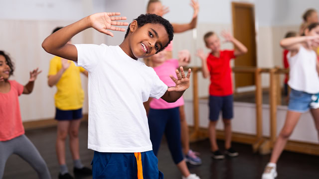 Smiling African American boy dancing during a group dance class in a local dance studio.