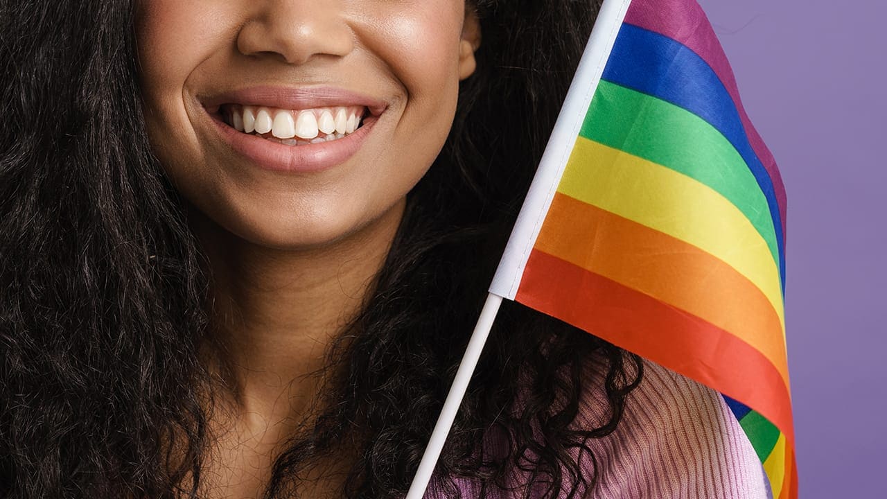 Smiling New Jersey resident holding rainbow pride flag.