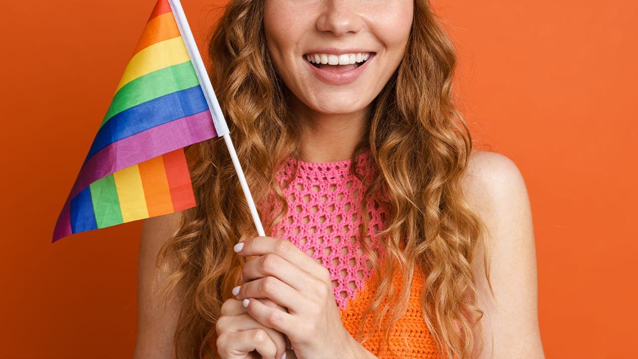Smiling New Jersey resident holding rainbow pride flag.