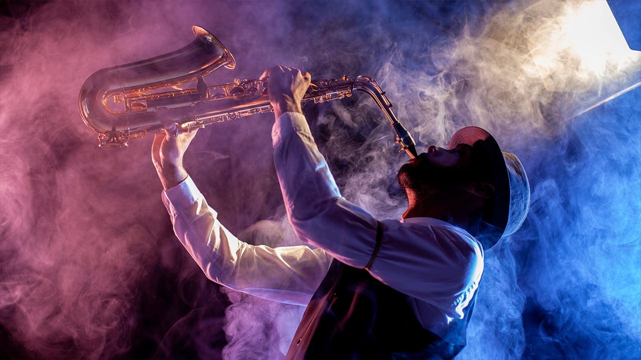 Talented saxophonist playing jazz wearing a sleeve garter in a smoke filled venue.