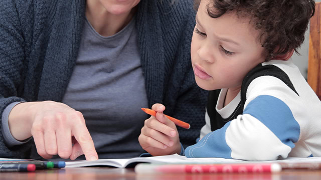 Teacher helping student with autism learn class material.