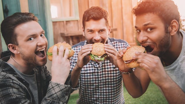 Three guys holding savory burgers at New Jersey food event.