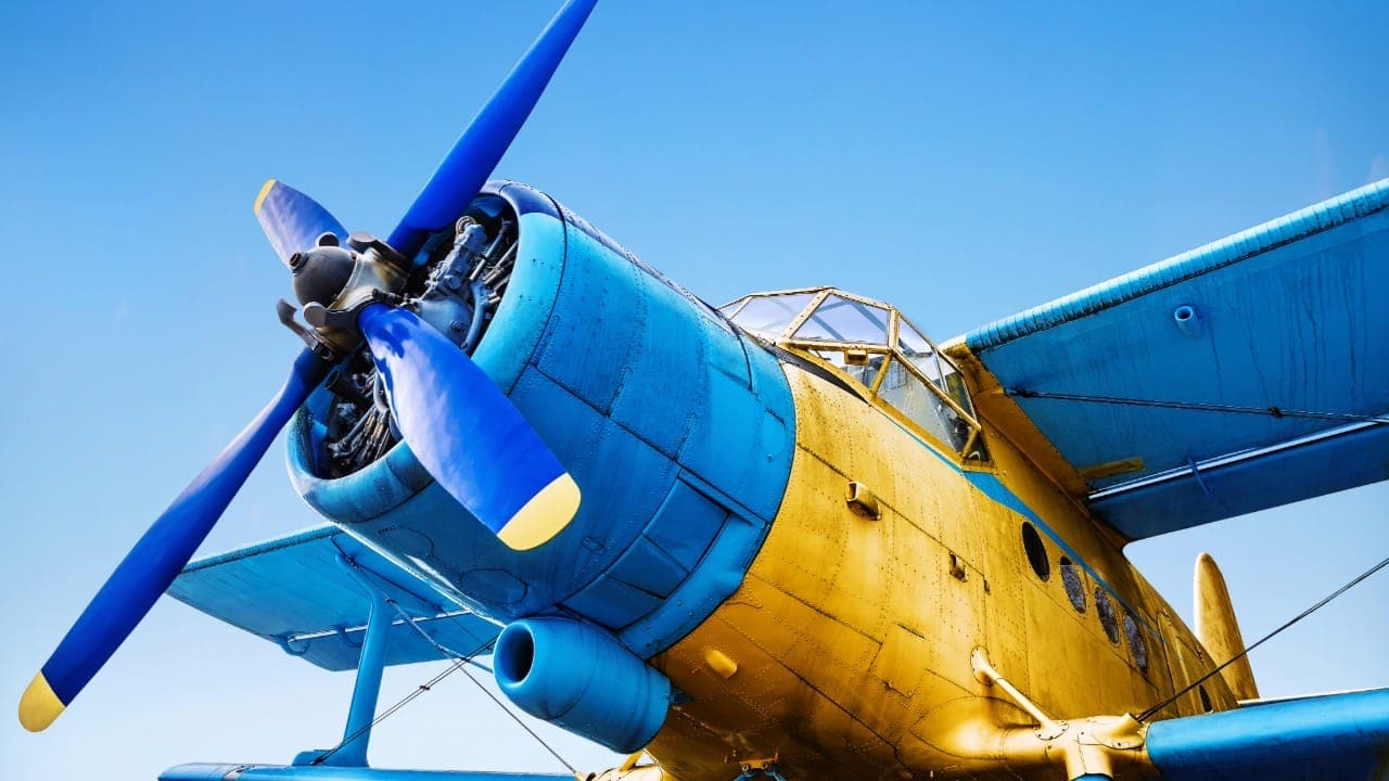 Vintage propeller plane against light blue sky.