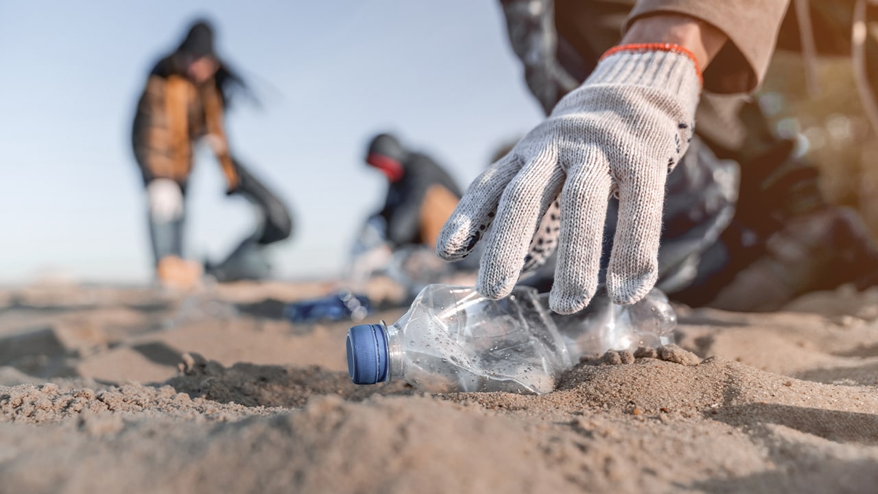 Volunteer collecting trash during New Jersey beach cleanup event.