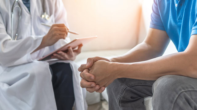 White doctor consulting with a white male patient.