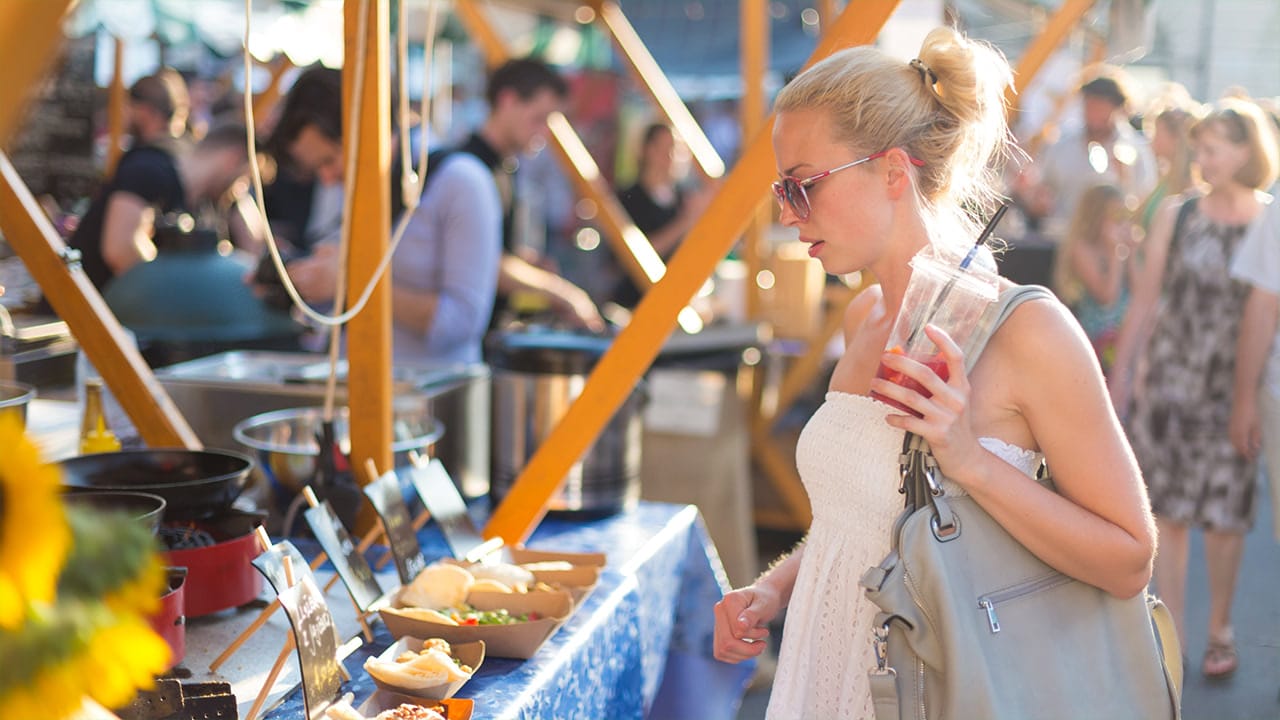 Woman at New Jersey street fair food vendor table deciding on which items to purchase.