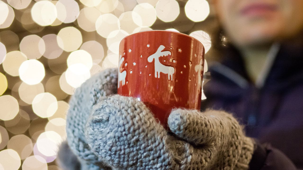 Woman holding a cup of holiday Christmas coffee or hot chocolate. Image produced by More Jersey.