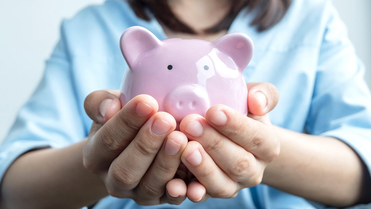 Woman holding piggy bank with intent of saving money. Image produced by More Jersey.