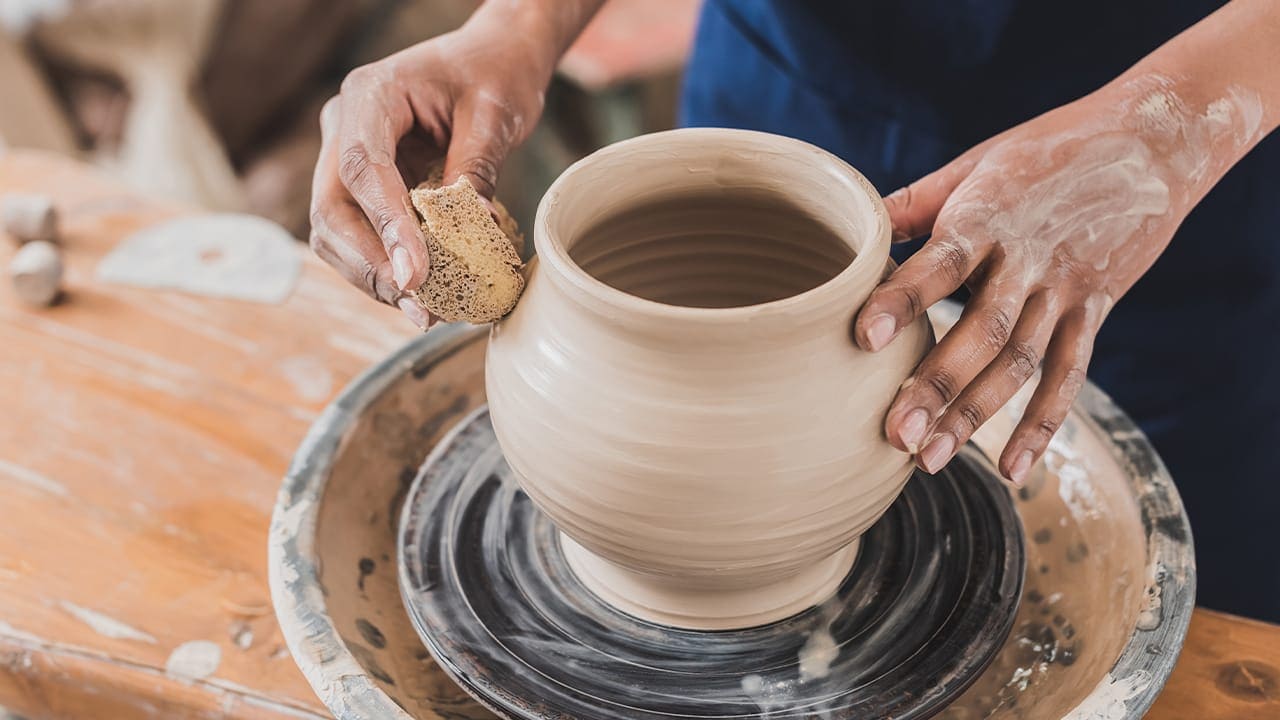 Woman using pottery wheel to make clay pot at New Jersey pottery class.