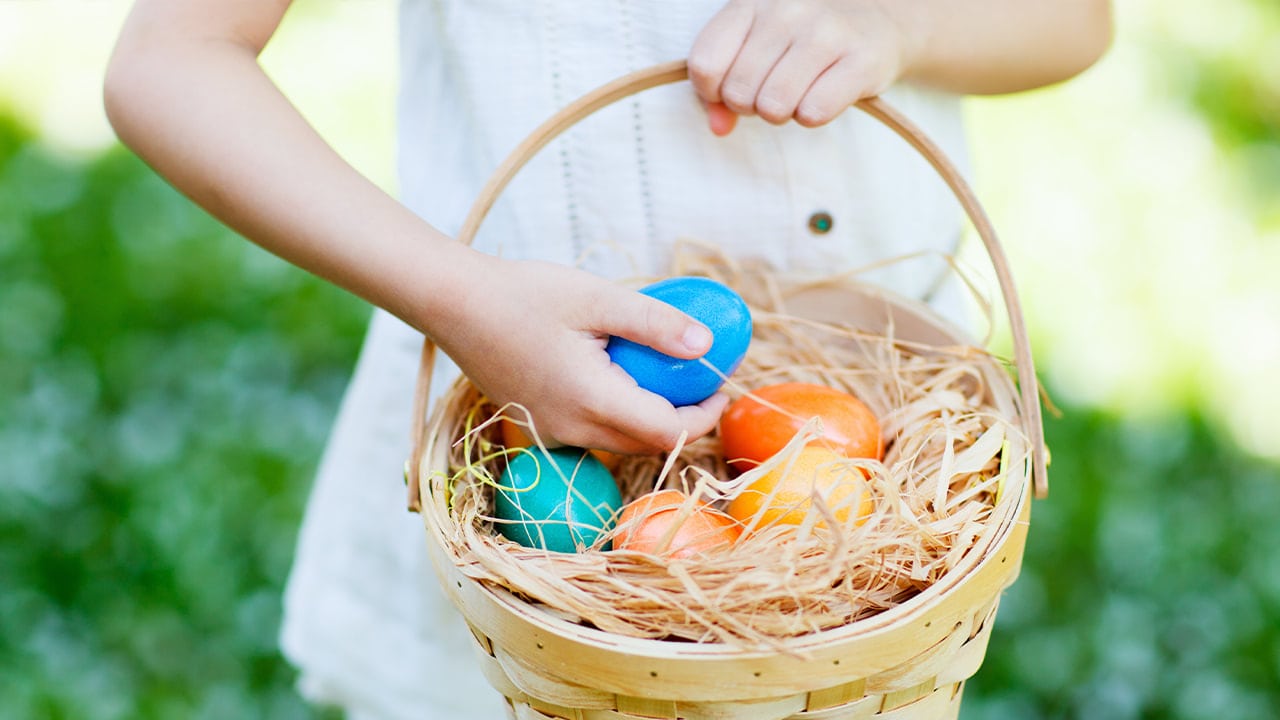 Young girl holding a basket with an assortment of colorful Easter eggs.