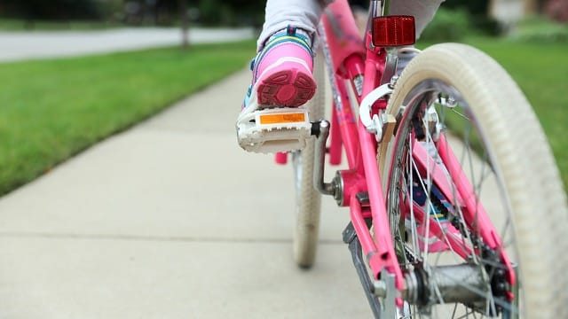Young girl riding bike on sidewalk.