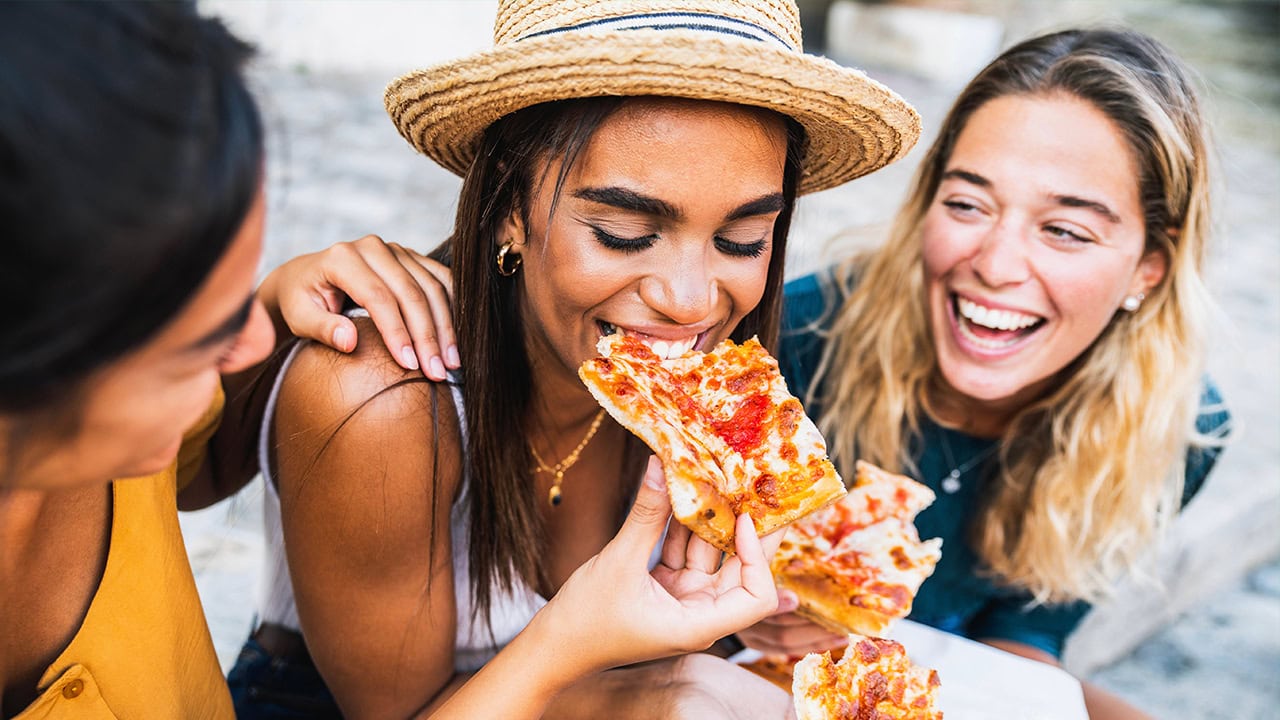 Young ladies eating pizza at outdoor New Jersey Italian event. Image produced by More Jersey.