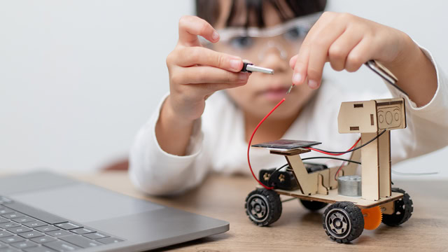 Young schoolgirl building and coding a robot car during New Jersey STEM class.